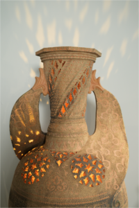 Pieza de barro calada y tallada a mano por el maestro alfarero Pablo Tito y Tito Martínez, con luz interior que proyecta sombras decorativas en la pared.